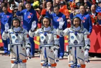 Para astronaut misi luar angkasa Shenzhou-20 Tiongkok (kiri) Wang Jie, Chen Zhongrui, dan Chen Dong melambaikan tangan saat upacara keberangkatan sebelum menaiki bus untuk membawa mereka ke pesawat luar angkasa Shenzhou-20 di Pusat Peluncuran Satelit. Foto: Pedro PARDO / AFP