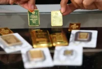 ILUSTRASI. Karyawan menunjukkan logam mulia emas murni di gerai Butik Emas Antam.