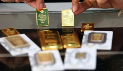 ILUSTRASI. Karyawan menunjukkan logam mulia emas murni di gerai Butik Emas Antam.