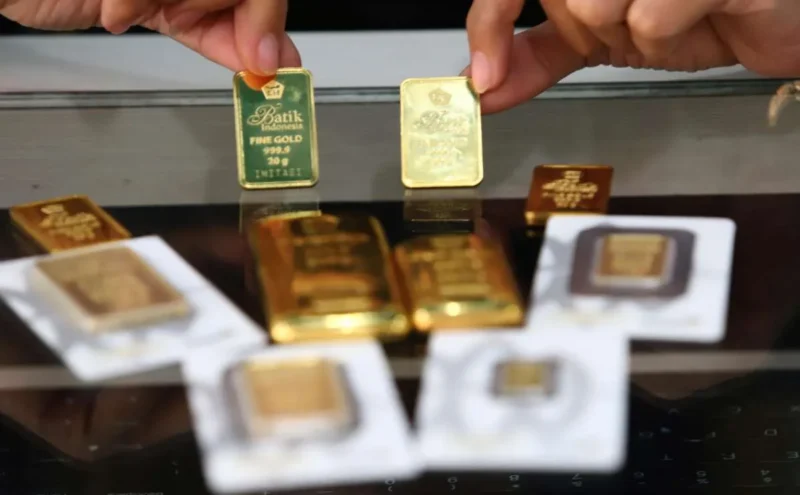 ILUSTRASI. Karyawan menunjukkan logam mulia emas murni di gerai Butik Emas Antam. 